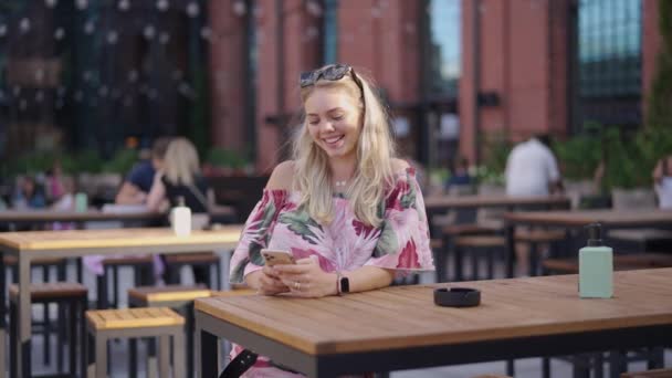 Счастливая женщина со смартфоном в кафе — стоковое видео