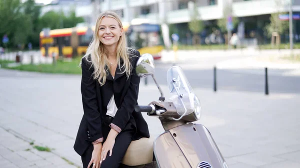 Onnellinen liikenainen istuu skootterilla — kuvapankkivalokuva