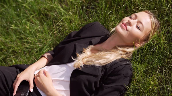 Businesswoman lying on grass in park — Stock Photo, Image