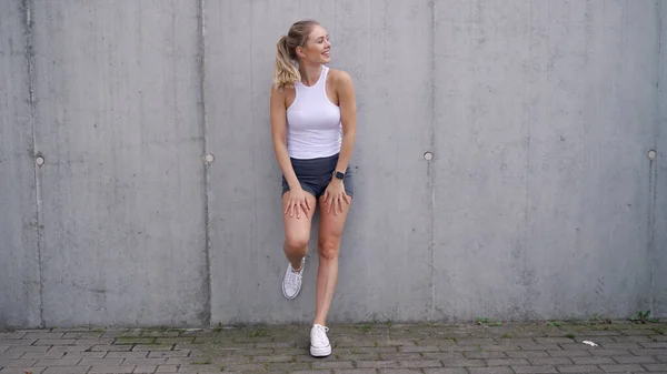 Atleta femenina optimista tomando un descanso cerca de la pared —  Fotos de Stock