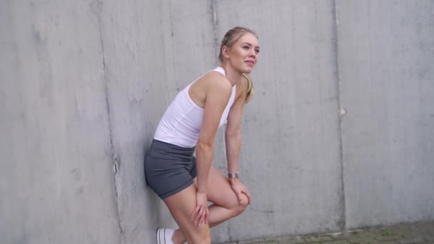 Sportkvinna vilar nära betongvägg på gatan — Stockvideo