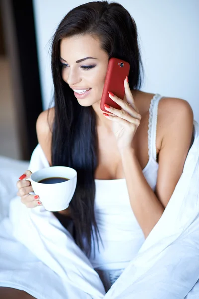 Güzel bir kadın yatakta mobil sohbet — Stok fotoğraf