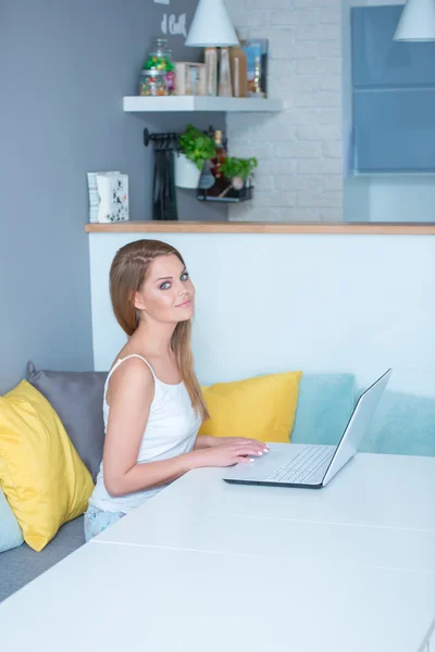 Junge Frau sitzt mit Laptop am Tisch — Stockfoto