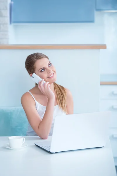 Mujer sonriente sentada en un escritorio tomando la llamada —  Fotos de Stock