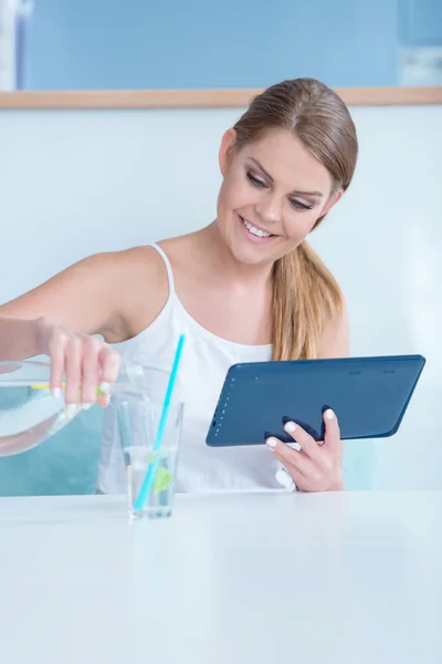 Durstige junge Frau gießt ein Glas Wasser ein — Stockfoto