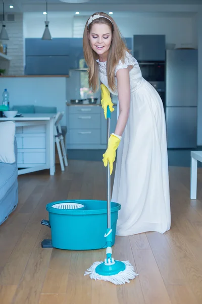 Kvinna iklädd brudklänning mopping golv — Stockfoto