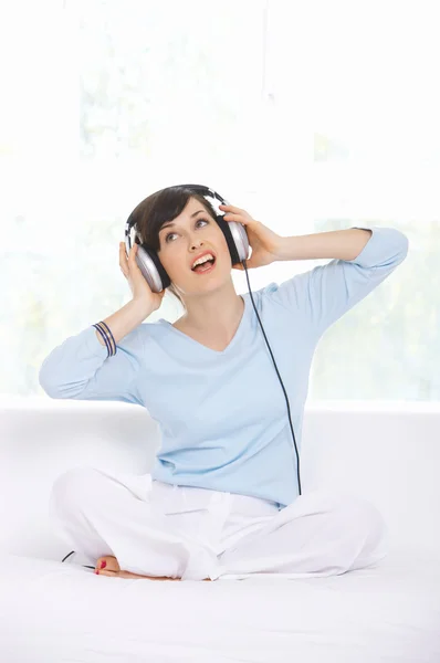 Mujer sentada usando auriculares y cantando —  Fotos de Stock