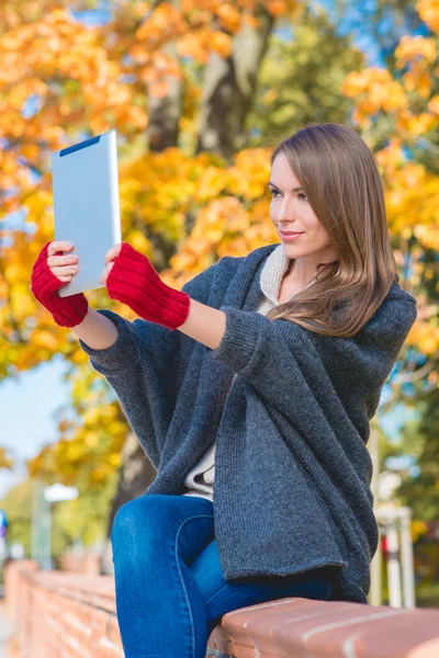 Mujer sosteniendo la tableta de computadora al aire libre en otoño —  Fotos de Stock