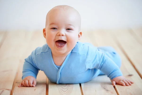 Bayi laki-laki lucu yang bahagia merangkak di lantai Stok Foto