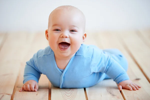 Schattige gelukkig babyjongen kruipen op de grond Stockfoto