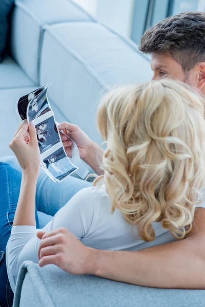 Gli amanti caucasici sul divano alla ricerca di belle foto — Foto Stock