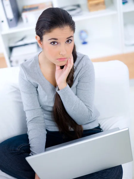 Lady sitting on sofa with concerned look — Stock Photo, Image