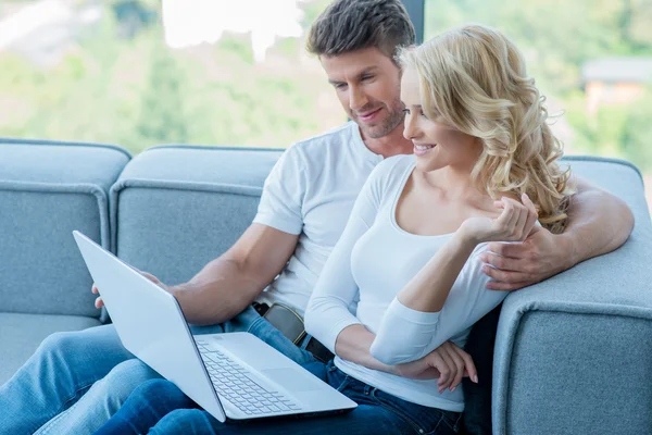 Casal relaxante em um sofá usando laptop — Fotografia de Stock