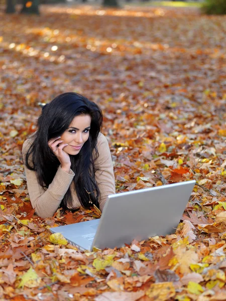 Mujer bastante sonriente acostada en el suelo con computadora portátil — Foto de Stock