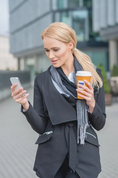 Geschäftsfrau beim Kaffeetrinken mit Telefon beschäftigt — Stockfoto