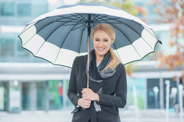 Lächelnde junge Frau unter einem offenen Regenschirm — Stockfoto