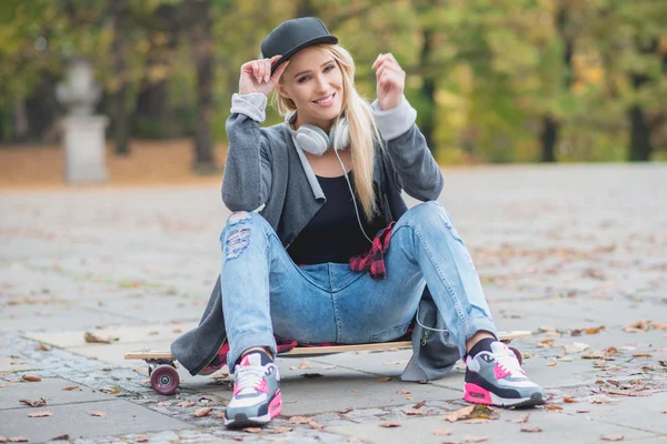 Kvinna med en söt leende sitter på skate board — Stockfoto