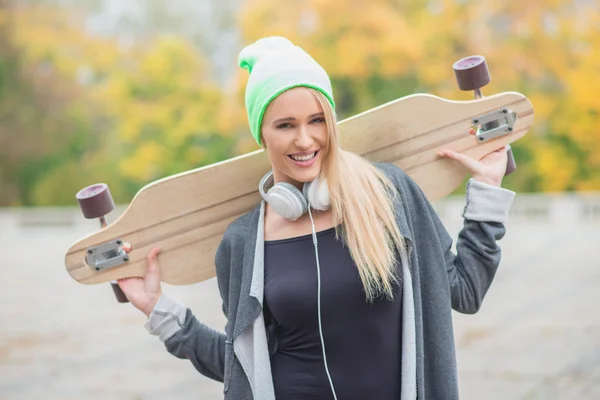 Happy young woman carrying a skate board — Stock Photo, Image