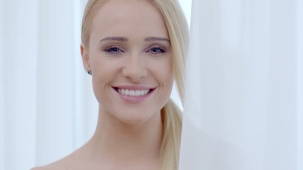 Mujer bastante sonriente detrás de la cortina blanca — Vídeos de Stock
