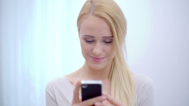 Mooie blonde vrouw texting op haar mobiele telefoon — Stockvideo