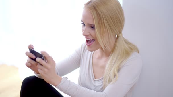 Emocionada joven leyendo un sms en su móvil — Vídeo de stock