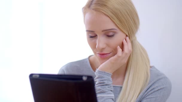 Allvarlig ung kvinna läser på hennes tablett — Stockvideo