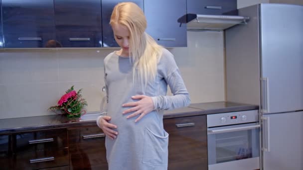 Zwangere jonge vrouw in haar keuken — Stockvideo