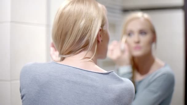 Mujer feliz poniendo maquillaje en frente de un espejo — Vídeo de stock