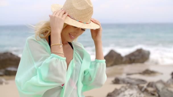 Retrato de una mujer rubia con sombrero de sol en la playa — Vídeos de Stock