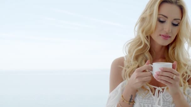 Blond Woman Holding Coffee Cup in front of Ocean — Stock Video