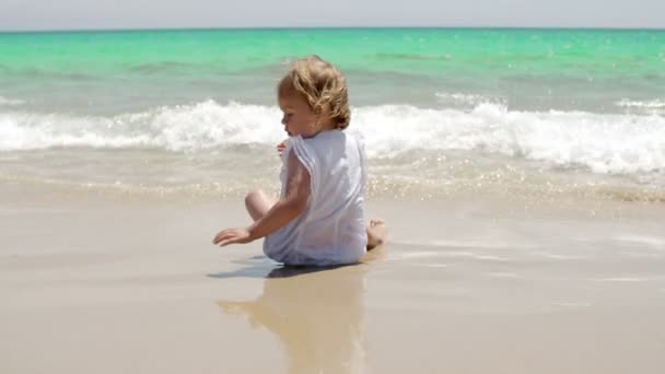 小さな女の子がサーフィンの端をうろついている — ストック動画