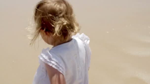 Klein blond meisje genieten op het strand — Stockvideo