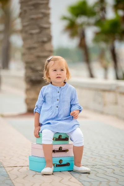 Little girl sitting on a stack of suitcases — Stockfoto