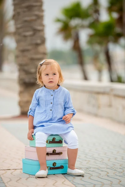 Little girl sitting on a stack of suitcases — Stockfoto