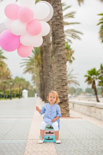 Happy little girl holding a bunch of balloons — Stockfoto