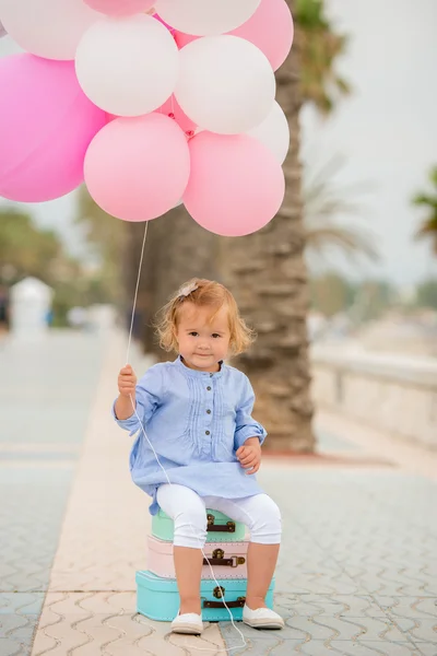 Happy little girl holding a bunch of balloons — Stockfoto