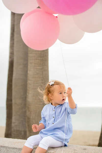 Cute little blond girl holding party balloons — Stock Photo, Image