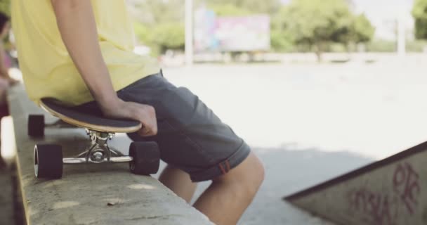 Homem sentado em um skate equilibrado em uma parede — Vídeo de Stock