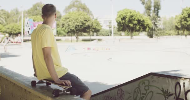 Mann sitzt auf Skateboard balanciert auf Wand — Stockvideo