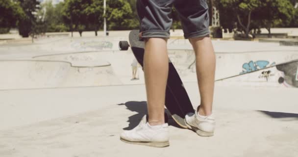 Mann steht mit seinem Longboard auf einem Skatepark — Stockvideo