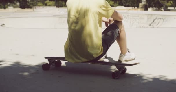 Homem sentado em seu longboard em um parque de skate — Vídeo de Stock