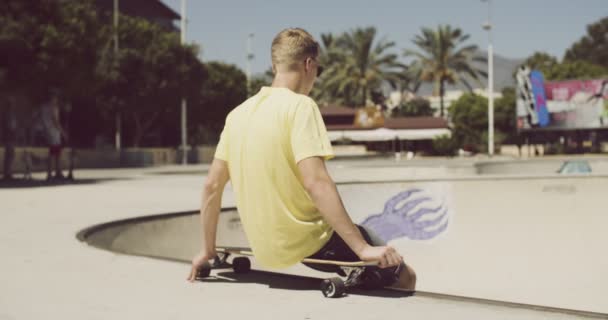 Adolescente está sentado en su Longboard — Vídeo de stock