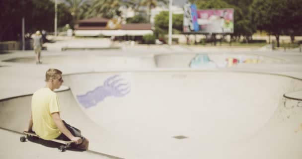 Bir longboard üzerinde oturan yalnız genç çocuk — Stok video