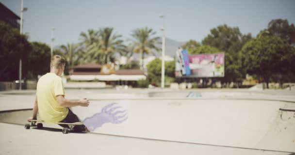 Ensam tonårspojke som sitter på en longboard — Stockvideo