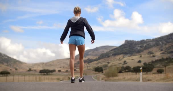 Девочка-фитнес, идущая по дороге в горах — стоковое видео