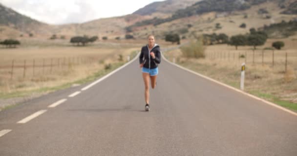 Девочка-фитнес бегает по дороге в горах — стоковое видео