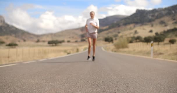Подходящая девочка, бегущая по горной дороге — стоковое видео