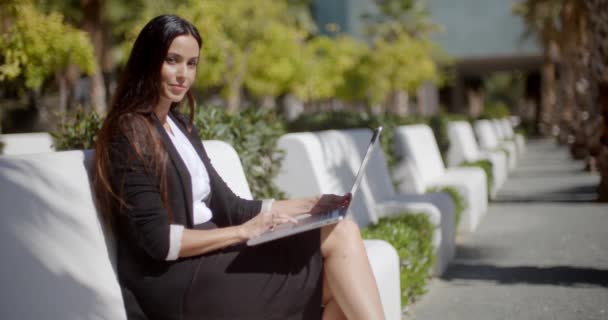 Young woman working on a laptop in the park — Stockvideo