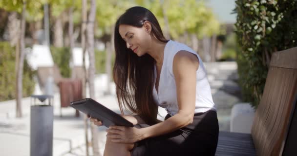 Femme d'affaires utilisant une tablette dans un parc urbain — Video