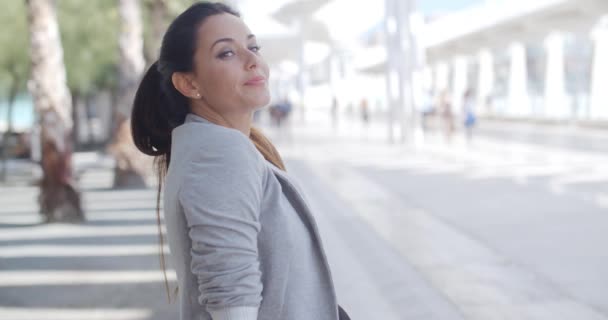 Elegante vrouw zittend op een bankje op een promenade — Stockvideo